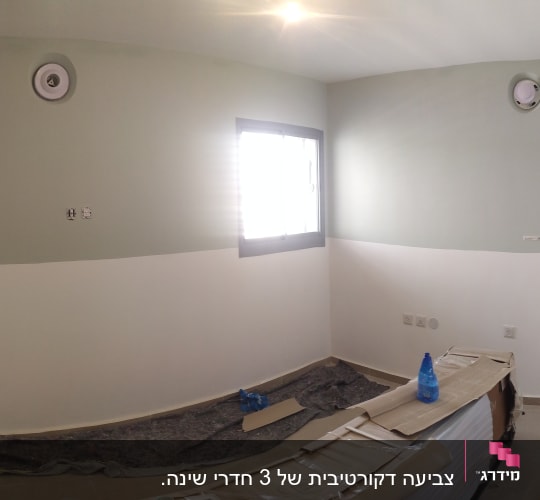 חדר צבוע בשני גוונים עם ציוד צביעה על הרצפה